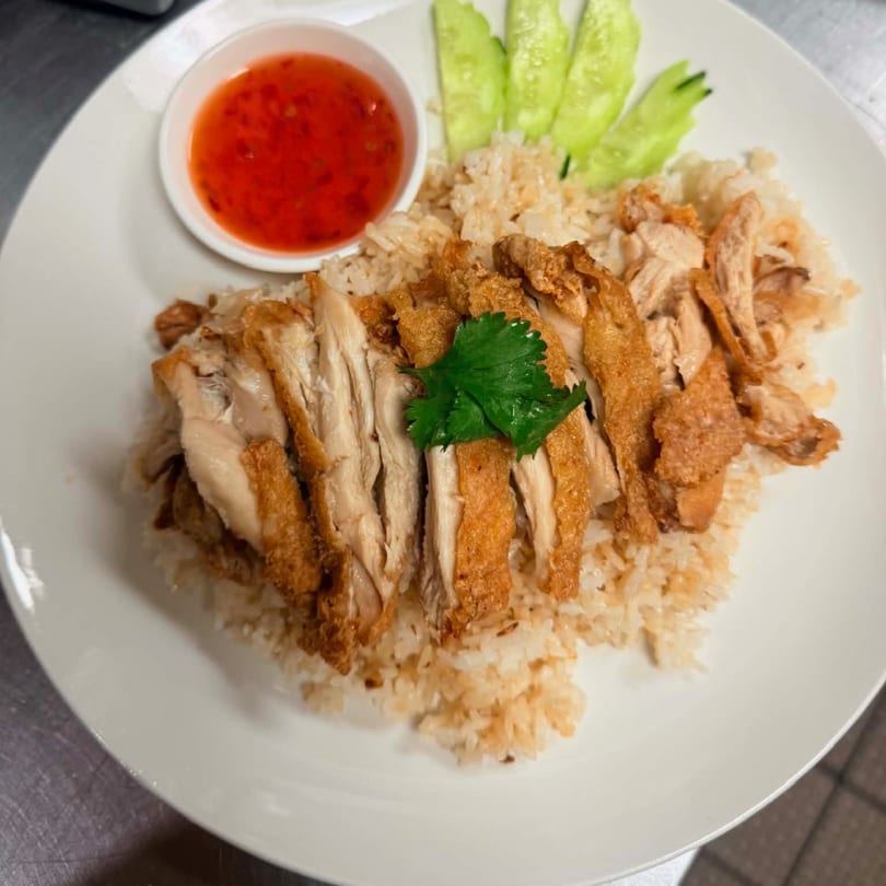 Crispy fried chicken over rice with sweet chili sauce and cucumber slices, a Thai dish from Red Jasmine.