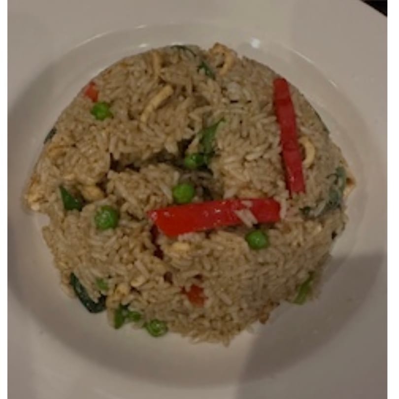 Thai fried rice with red peppers, green peas, and chicken on a white plate.
