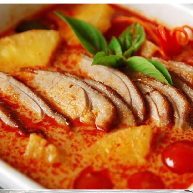 Red Jasmine Thai red curry with sliced duck, pineapple, cherry tomatoes, and basil leaves.